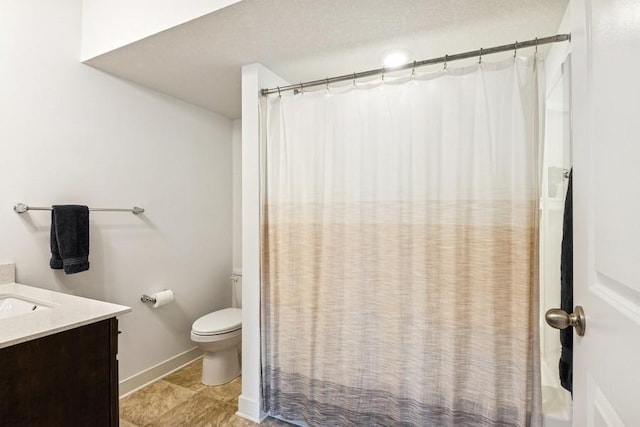 full bathroom with toilet, vanity, and baseboards