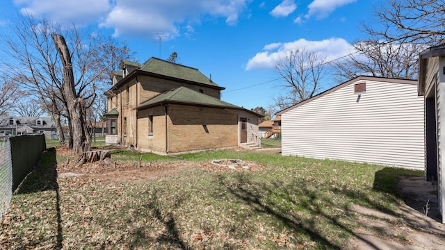 view of property exterior featuring fence, a yard, an outdoor fire pit, and brick siding
