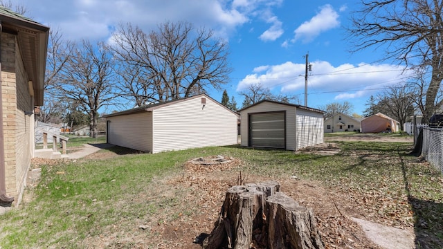 view of yard featuring a detached garage, an outdoor structure, an outdoor fire pit, and a storage shed