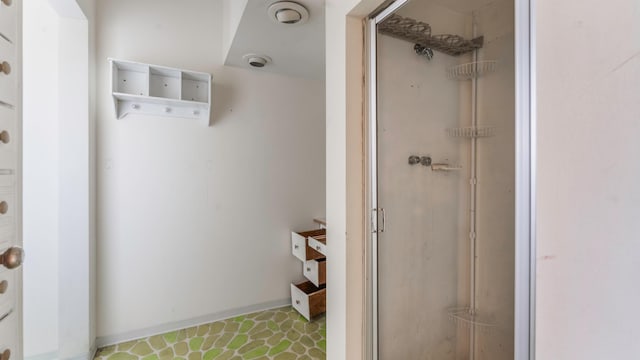 bathroom featuring baseboards, tile patterned floors, and a shower stall