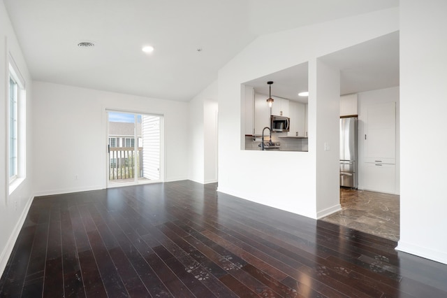 unfurnished living room featuring baseboards, a sink, dark wood finished floors, and lofted ceiling