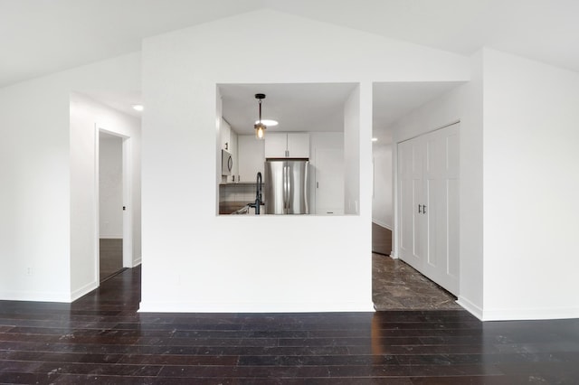 unfurnished living room featuring baseboards, dark wood finished floors, and vaulted ceiling