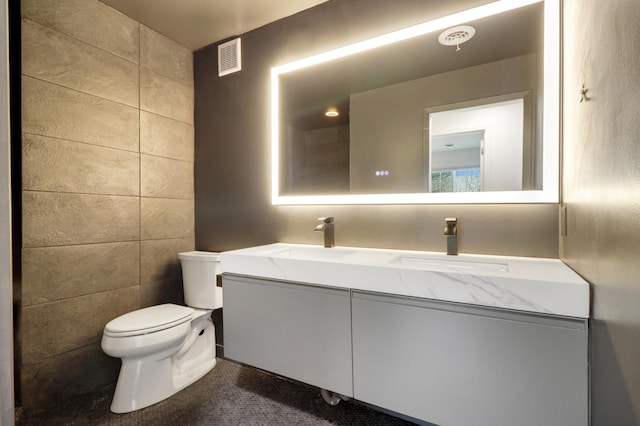full bathroom featuring a sink, toilet, double vanity, and visible vents