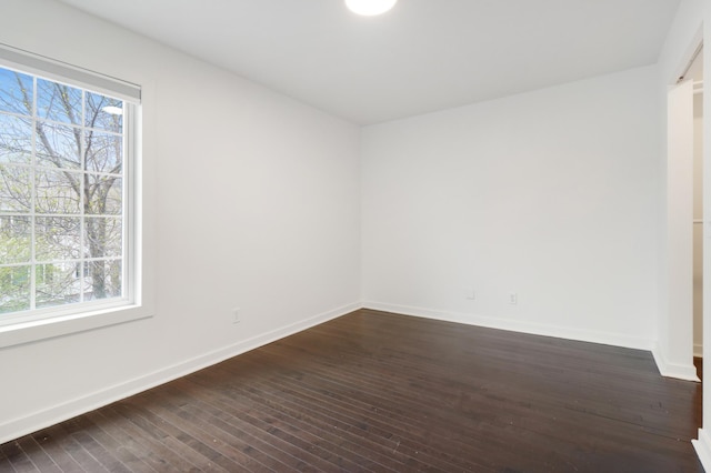 empty room with baseboards and dark wood-style floors