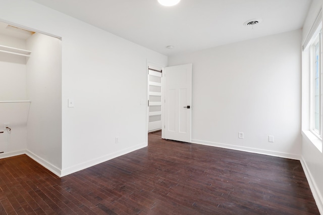 unfurnished bedroom with baseboards, hardwood / wood-style floors, and a spacious closet