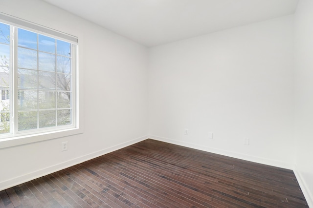 empty room with baseboards, dark wood-style flooring, and a healthy amount of sunlight