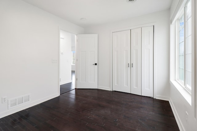 unfurnished bedroom with visible vents, multiple windows, and wood finished floors