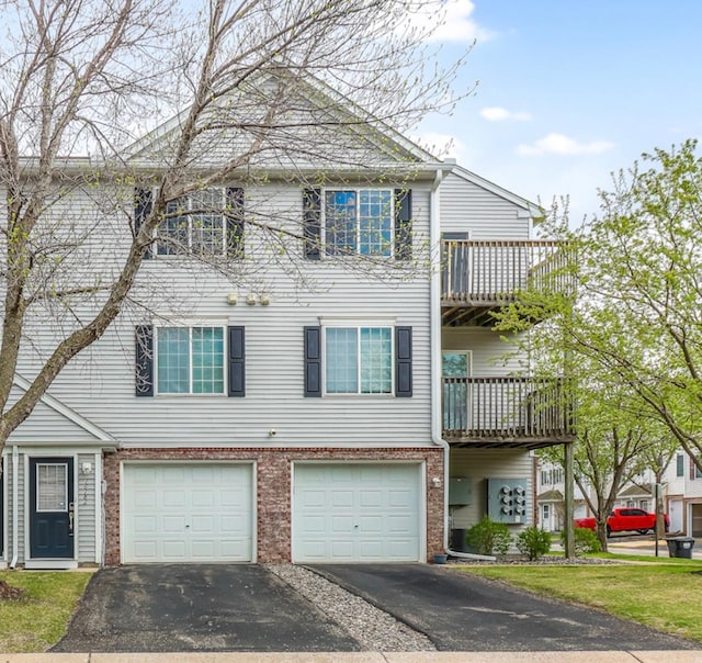 townhome / multi-family property featuring brick siding, driveway, and a garage