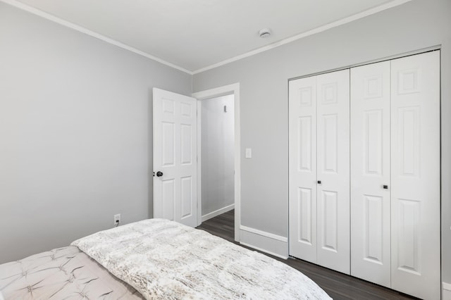 bedroom featuring baseboards, ornamental molding, a closet, and dark wood-style floors