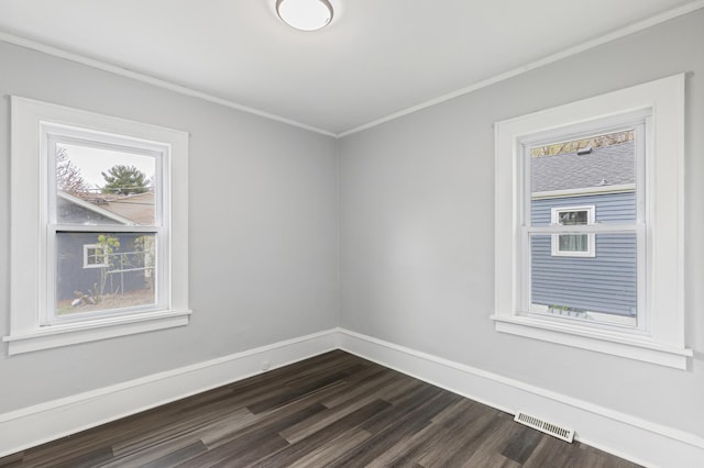 empty room with dark wood-style floors, baseboards, visible vents, and ornamental molding