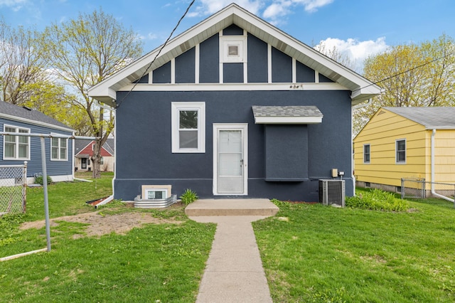 bungalow-style house with stucco siding, fence, a front yard, and cooling unit