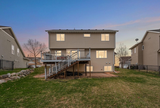 rear view of property featuring fence, a wooden deck, a yard, and stairway