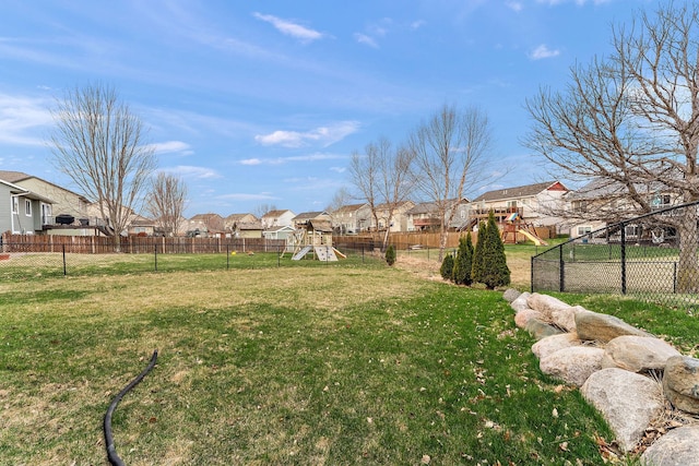 view of yard with a fenced backyard, a playground, and a residential view