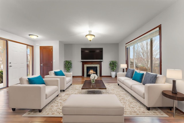living area featuring light wood-type flooring and a warm lit fireplace