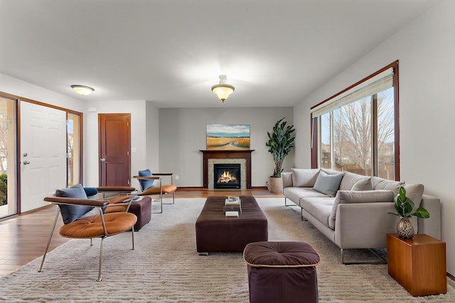 living room with a warm lit fireplace and wood finished floors
