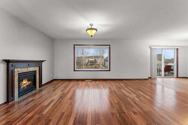 unfurnished living room with a glass covered fireplace, a healthy amount of sunlight, and hardwood / wood-style floors