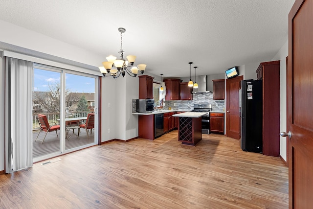 kitchen featuring a notable chandelier, light countertops, light wood-style flooring, wall chimney exhaust hood, and black appliances