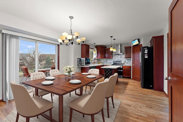 dining room with a healthy amount of sunlight, light wood finished floors, and a chandelier