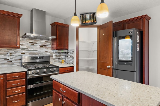 kitchen with decorative backsplash, appliances with stainless steel finishes, hanging light fixtures, reddish brown cabinets, and wall chimney exhaust hood