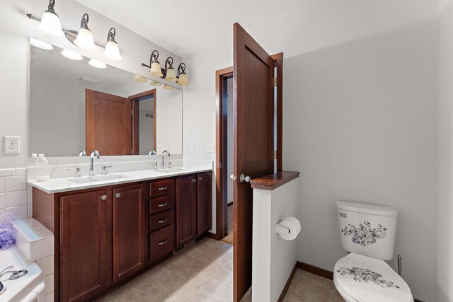 bathroom featuring double vanity, toilet, a washtub, and a sink
