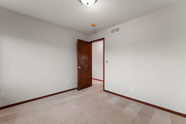 unfurnished room featuring visible vents, a textured ceiling, baseboards, and light carpet