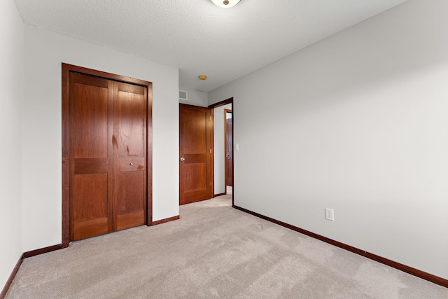 unfurnished bedroom with baseboards, a closet, and light carpet