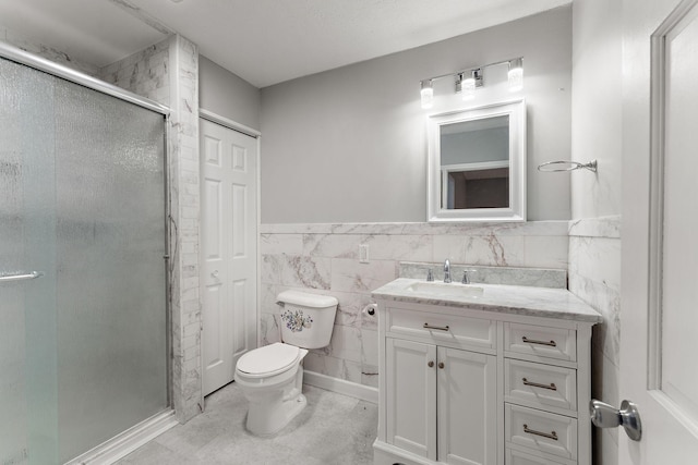bathroom featuring wainscoting, vanity, toilet, tile walls, and a stall shower