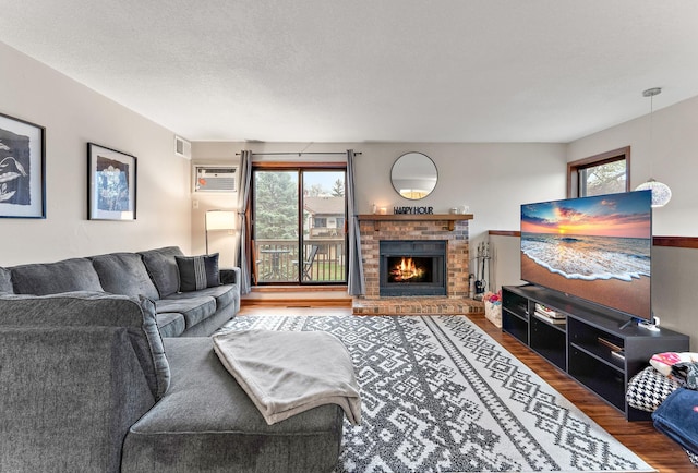 2071 Parkside Dr Unit 30, Saint Paul, MN 55119 - living room featuring plenty of natural light, wood finished floors, a brick fireplace, and a wall mounted air conditioner