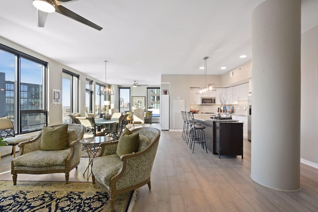 living area with recessed lighting, a ceiling fan, light wood finished floors, and a wealth of natural light