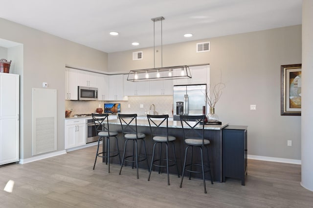 kitchen featuring appliances with stainless steel finishes, light wood-type flooring, and visible vents