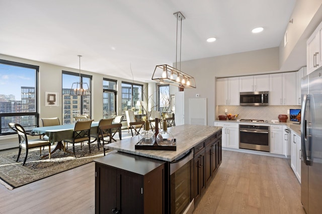 kitchen with light wood-type flooring, backsplash, a wealth of natural light, and stainless steel appliances
