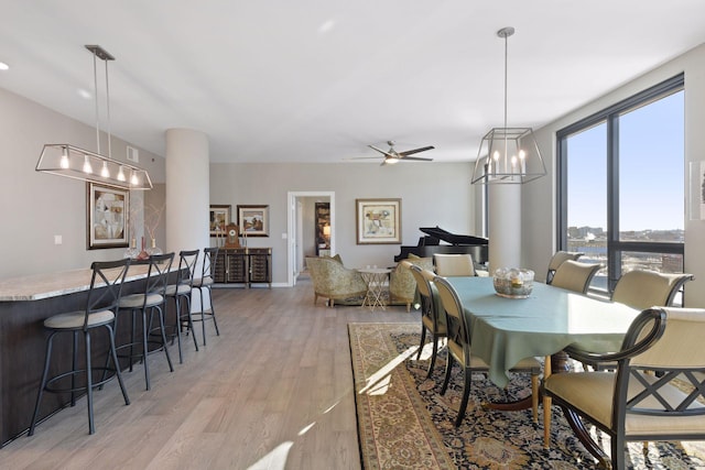 dining space with ceiling fan with notable chandelier and light wood finished floors