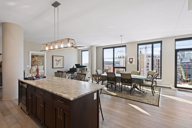 kitchen featuring wine cooler, dark brown cabinets, light countertops, light wood finished floors, and hanging light fixtures