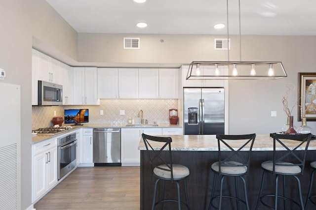kitchen featuring a sink, appliances with stainless steel finishes, a breakfast bar, and visible vents