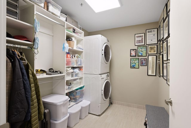clothes washing area featuring laundry area, stacked washer and dryer, and baseboards
