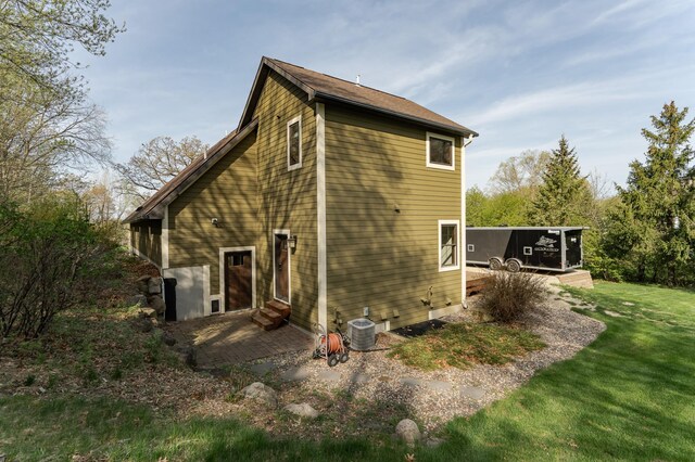rear view of property featuring central AC, a lawn, a wooden deck, entry steps, and a patio