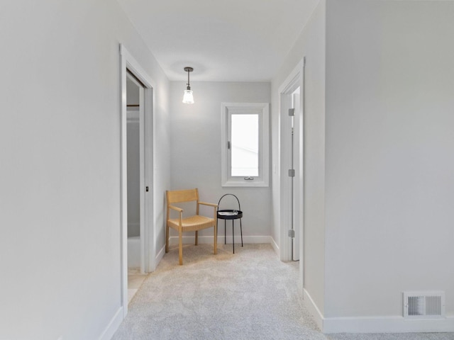 hallway featuring carpet floors, baseboards, and visible vents