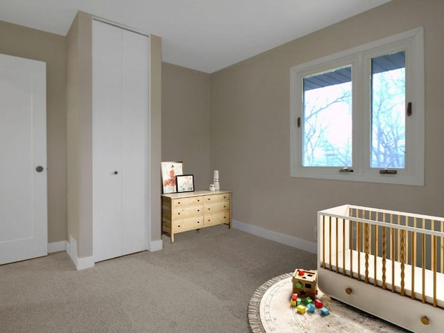 bedroom with a nursery area, baseboards, light colored carpet, and a closet