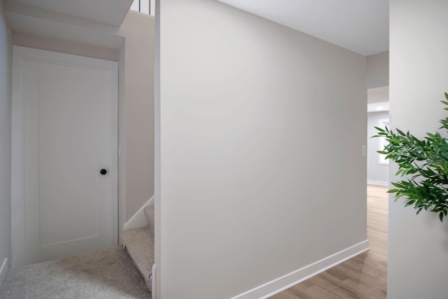 hallway with baseboards, light wood finished floors, and stairway