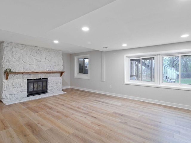 unfurnished living room featuring baseboards, light wood-style flooring, recessed lighting, and a stone fireplace