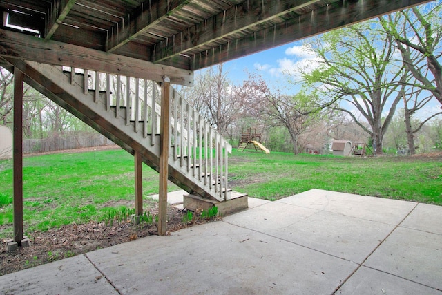 view of patio featuring stairs, a playground, and a storage shed