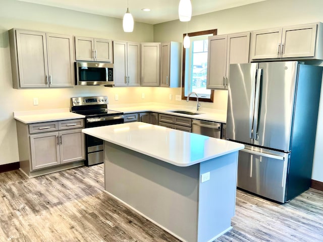 kitchen featuring a sink, stainless steel appliances, gray cabinets, light wood-type flooring, and light countertops
