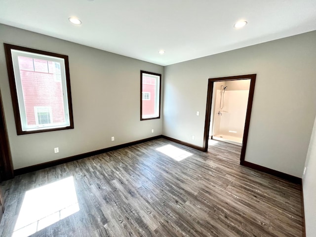 spare room with baseboards, a healthy amount of sunlight, and dark wood-type flooring