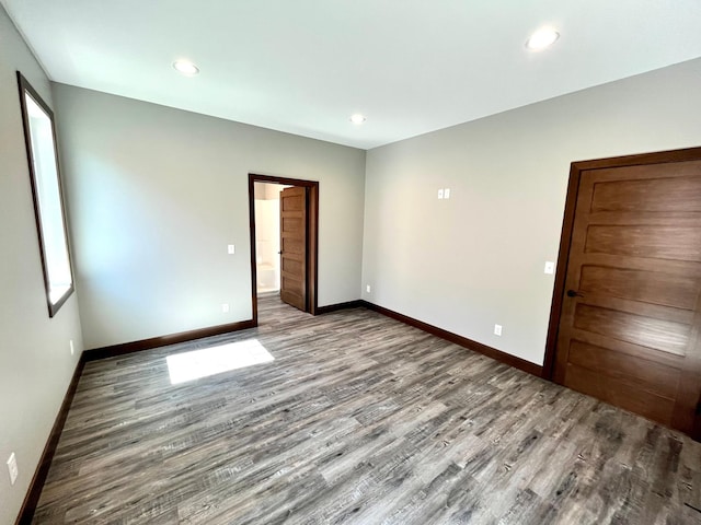 spare room featuring baseboards, recessed lighting, and wood finished floors