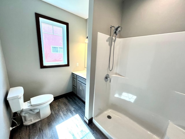 full bathroom with toilet, wood finished floors, vanity, a stall shower, and baseboards