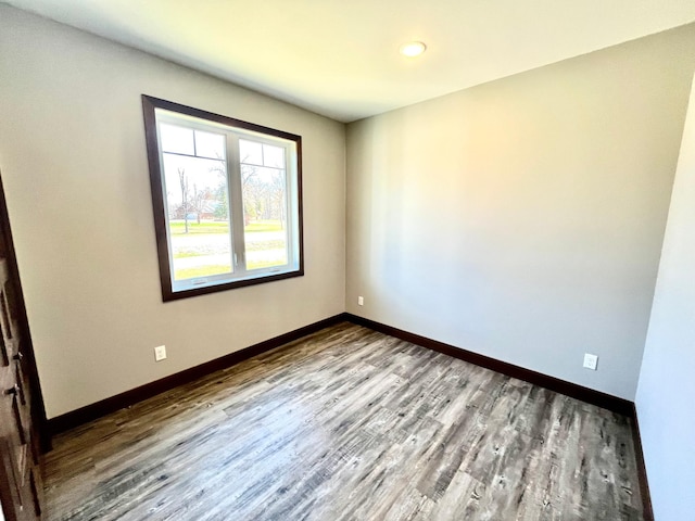 empty room featuring baseboards, recessed lighting, and wood finished floors