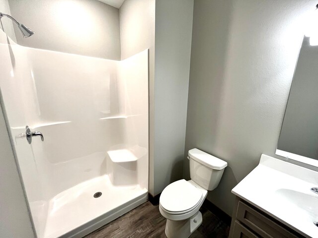 full bathroom featuring vanity, toilet, a shower, and wood finished floors