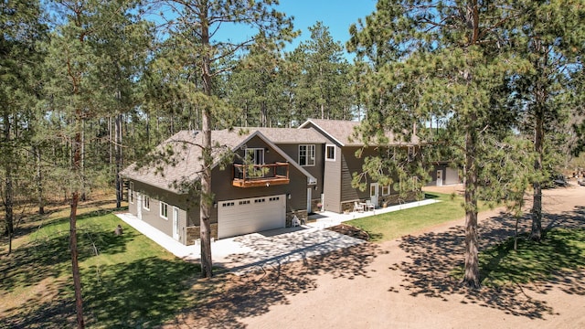 chalet / cabin featuring a front lawn, driveway, a garage, and a balcony