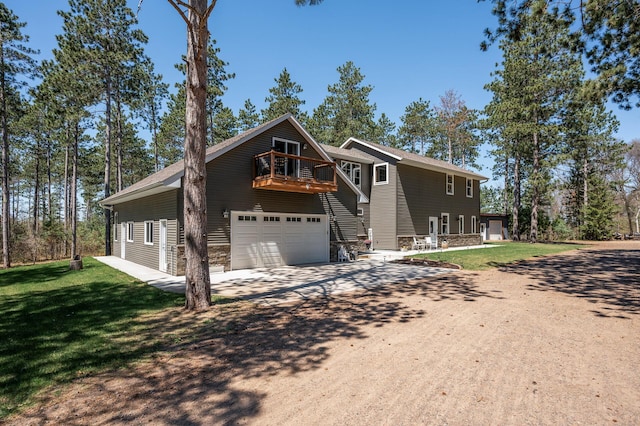 chalet / cabin with concrete driveway, a front yard, a garage, and a balcony