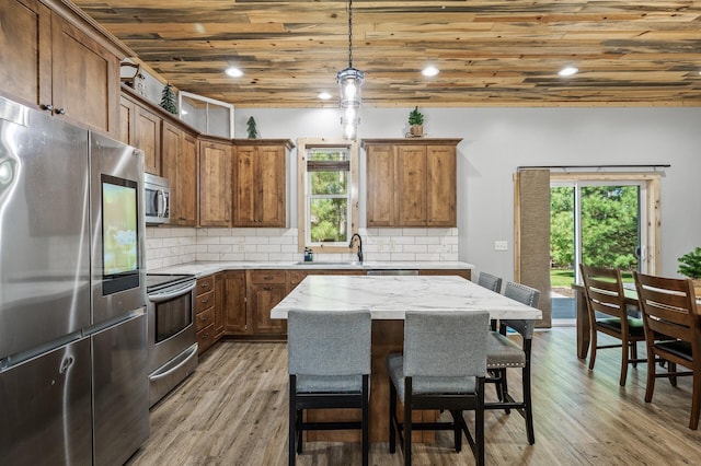 kitchen with stainless steel appliances, wood ceiling, plenty of natural light, and brown cabinets